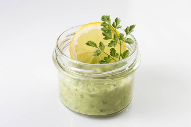Meksika sosu guacamole limon dilimi ve maydanoz üzerinde beyaz izole bir kavanoza.