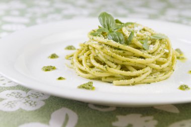 Beyaz tabak içinde yabani sarımsak pesto sos ve parmesan ile spagetti makarna Bucatini