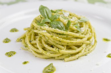 Beyaz tabak içinde yabani sarımsak pesto sos ve parmesan ile spagetti makarna Bucatini