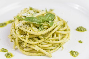 Beyaz tabak içinde yabani sarımsak pesto sos ve parmesan ile spagetti makarna Bucatini