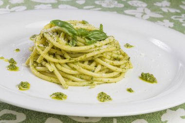 Beyaz tabak içinde yabani sarımsak pesto sos ve parmesan ile spagetti makarna Bucatini