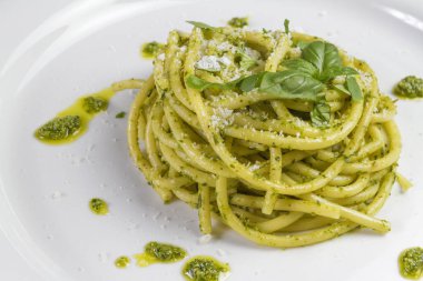 Beyaz tabak içinde yabani sarımsak pesto sos ve parmesan ile spagetti makarna Bucatini