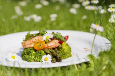 Karides, kuşkonmaz ve brokoli ile yenilebilir papatya çiçekler. Seçici odak. Açık fotoğraf.