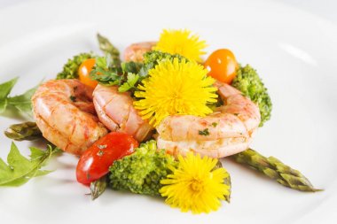 Karides, kuşkonmaz ve brokoli yenilebilir karahindiba çiçekli. Seçici odak.