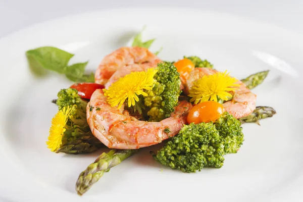 Prawns, asparagus and broccoli with edible dandelion flowers. Selective focus.