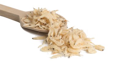 Beyaz arka planda izole edilmiş tahta kaşıkta kurutulmuş karidesler. yemek malzemesi.