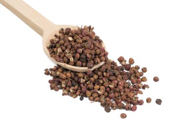 Beyaz arka planda izole edilmiş tahta kaşıkta sichuan biberi. yemek malzemesi.