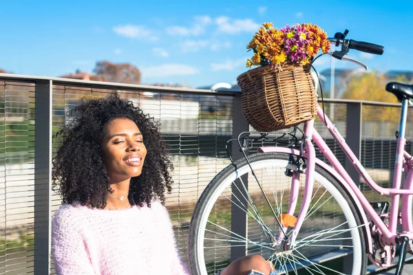 Schwarze junge Frau sitzt mit ihrem Oldtimer-Fahrrad am Fluss — Stockfoto