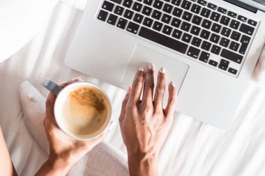 bir kahve içme ve onun bilgisayar ile çalıştığı gülümseyen kadın