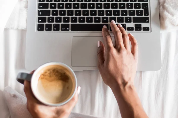 Mujer sonriendo tomando un café y trabajando con su computadora en