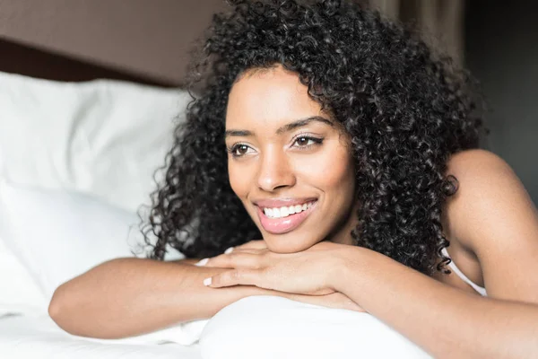 Kobieta szczęśliwa na łóżku uśmiechając się i rozciąganie, patrząc na kamery w t — Zdjęcie stockowe