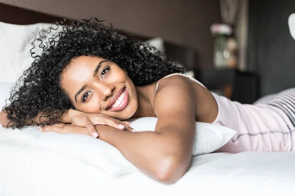 Μαύρο γυναίκα ευτυχισμένη στο κρεβάτι χαμογελώντας και τέντωμα βλέπουν camer — Φωτογραφία Αρχείου