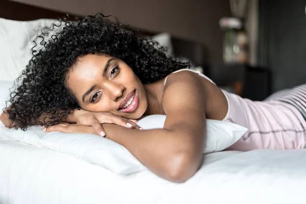 Czarny Kobieta szczęśliwy na łóżku uśmiechając się i rozciąganie, ogląda camer — Zdjęcie stockowe