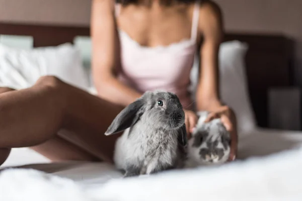 Woman playing with bunnies on bed — Stock Photo, Image