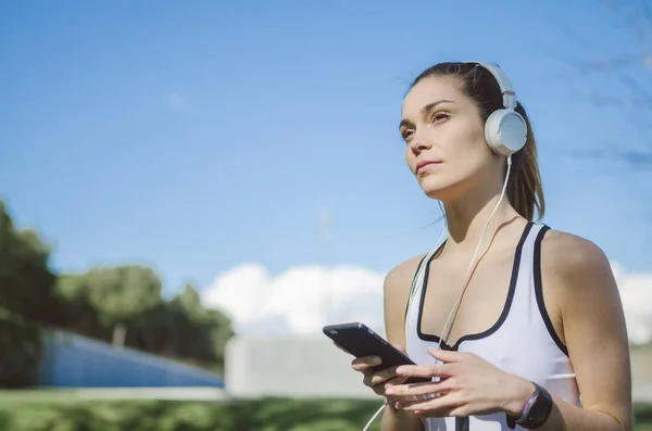 Zdrowa kobieta, odpoczynku i słuchania muzyki z telefonu komórkowego podczas wykonywania jogi i ćwiczeń — Zdjęcie stockowe