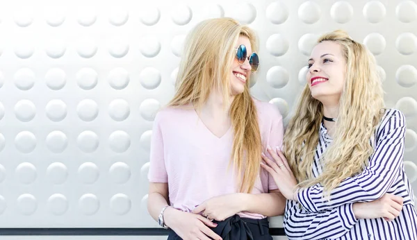 Dois estudantes loiros amigos rindo usando telefone celular e tablet — Fotografia de Stock