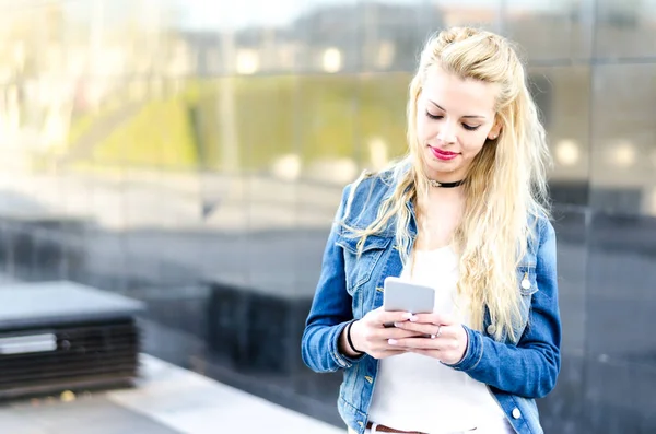 Feliz rubia joven al aire libre utilizando su teléfono móvil aislado — Foto de Stock