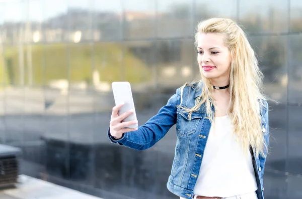 Aislado feliz rubia joven al aire libre utilizando su teléfono móvil — Foto de Stock