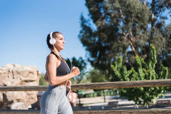 Sportowy piękne Młoda kobieta działa jogging w parku na zewnątrz słuchania muzyki — Zdjęcie stockowe