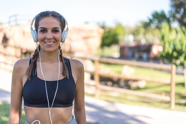 Portret kobiety robi sport odpoczynku odkryty, uśmiechając się i słuchanie muzyki z bliska — Zdjęcie stockowe