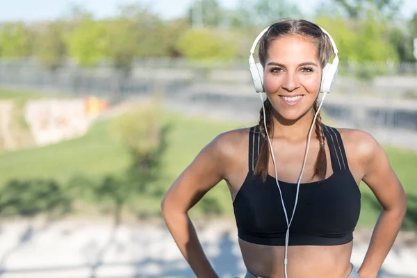 Portret kobiety robi sport odpoczynku odkryty, uśmiechając się i słuchanie muzyki z bliska — Zdjęcie stockowe