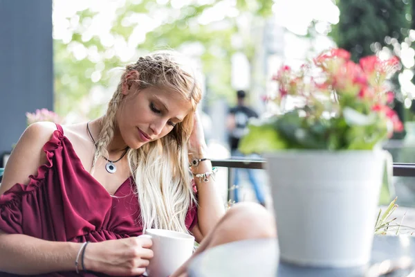 Kaunis blondi nainen juo kupin kahvia terassilla . — kuvapankkivalokuva