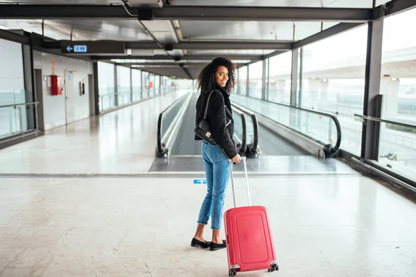 Mujer negra en la pasarela en movimiento en el aeropuerto con un sui rosa — Foto de Stock