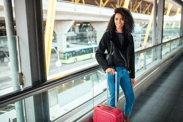 Donna nella passerella in movimento all'aeroporto con una valigia rosa . — Foto Stock