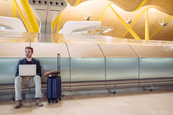 Havaalanında bir lapto ile çalışma oturan genç çekici adam