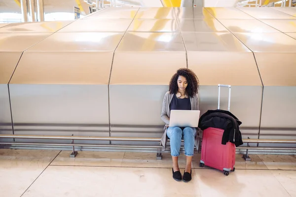 Atrakcyjna kobieta na lotnisku siedząc i praca z laptopem — Zdjęcie stockowe