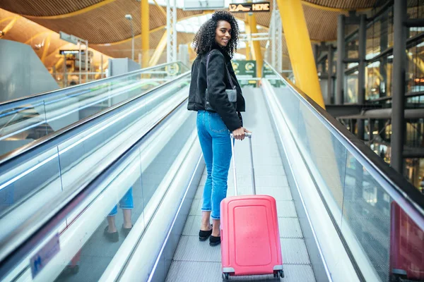 Mulher negra na passarela em movimento no aeroporto com um sui rosa — Fotografia de Stock