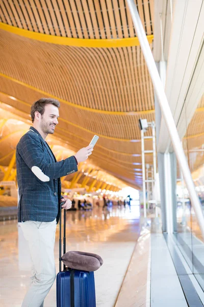 Homem usando telefone celular no aeroporto olhando através da janela — Fotografia de Stock