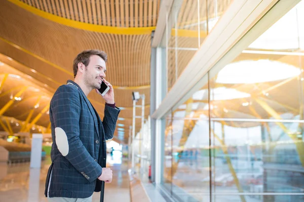 Man using mobile phone at the airport looking trough the window — Stock Photo, Image