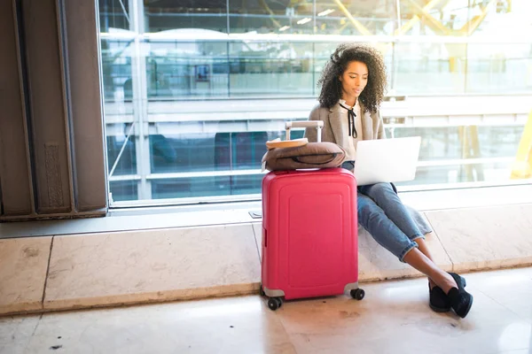 Mujer negra que trabaja con el ordenador portátil en el aeropuerto esperando en el wi — Foto de Stock