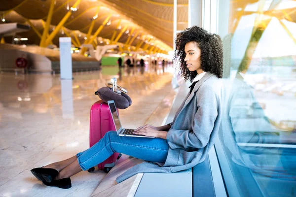 Žena pracující s přenosným počítačem na letišti čeká na okno — Stock fotografie