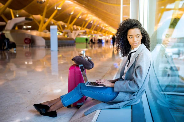 Kobieta, pracująca z laptopa na lotnisku czeka na okna — Zdjęcie stockowe