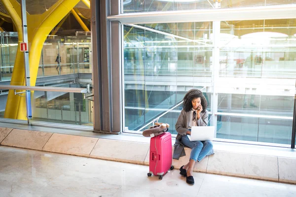 공항 좌석에 휴대 전화 및 노트북을 사용 하 여 흑인 여성 — 스톡 사진
