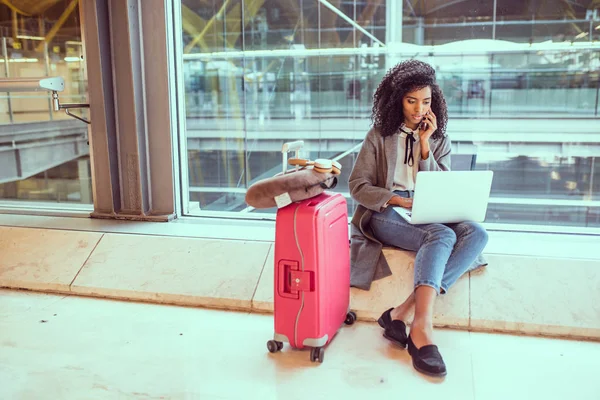 Mujer usando el teléfono móvil y el ordenador portátil en el aeropuerto sentado en th — Foto de Stock