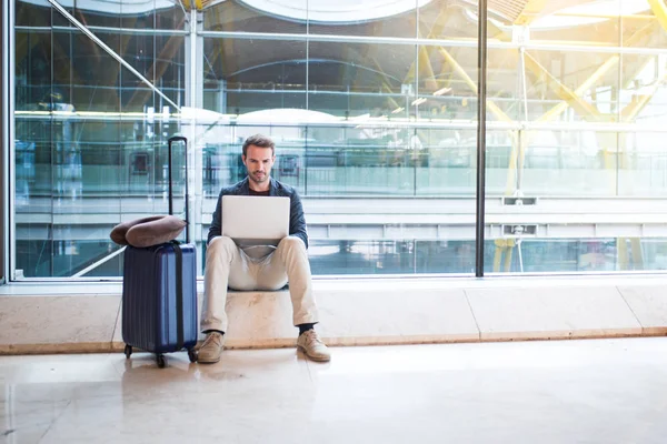 havaalanında kullanarak dizüstü bilgisayar ve cep telefonu yanında oturan adam