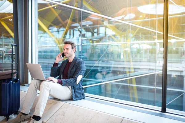 Man sitting at the airport using laptop and mobile phone next to — Stock Photo, Image