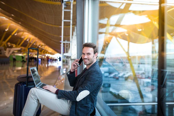 Man sitting at the airport using laptop and mobile phone next to — Stock Photo, Image