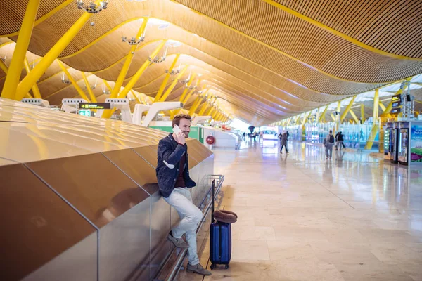 Jovem esperando e usando telefone celular no aeroporto — Fotografia de Stock