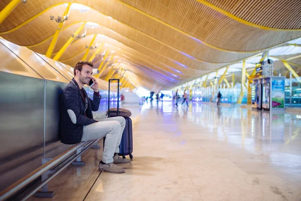 若い男、空港で待っていると使用しての携帯電話 — ストック写真