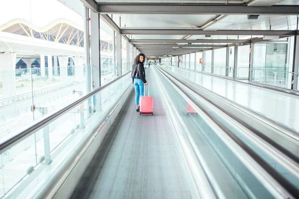 Mujer negra en la pasarela en movimiento en el aeropuerto con un sui rosa — Foto de Stock