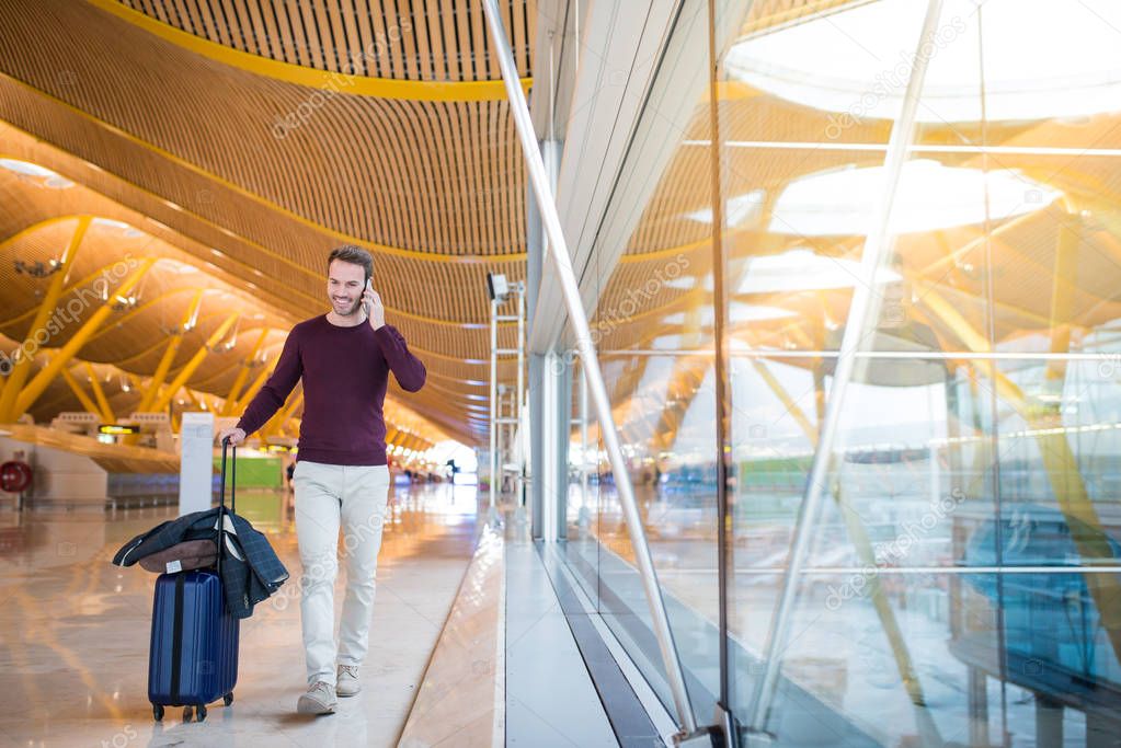 man front walking at the airport using mobile phone