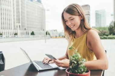 Genç iş kadını bilgisayarda ve cep telefonu