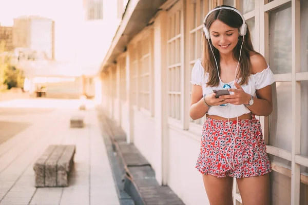 Mujer joven y feliz escuchando música en el teléfono móvil — Foto de Stock