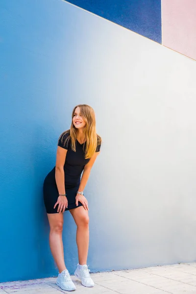 Szczęśliwy piękna młoda kobieta stwarzających przez kolorowe ściany — Zdjęcie stockowe