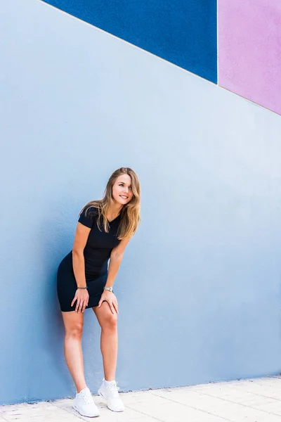 Happy beautiful young woman posing by a colorful wall — Stock Photo, Image