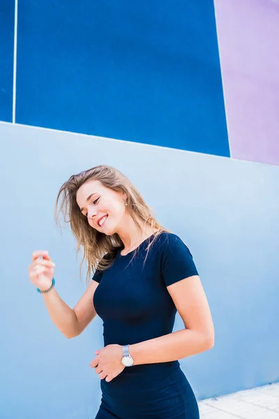 Joyeux belle jeune femme posant par un mur coloré — Photo